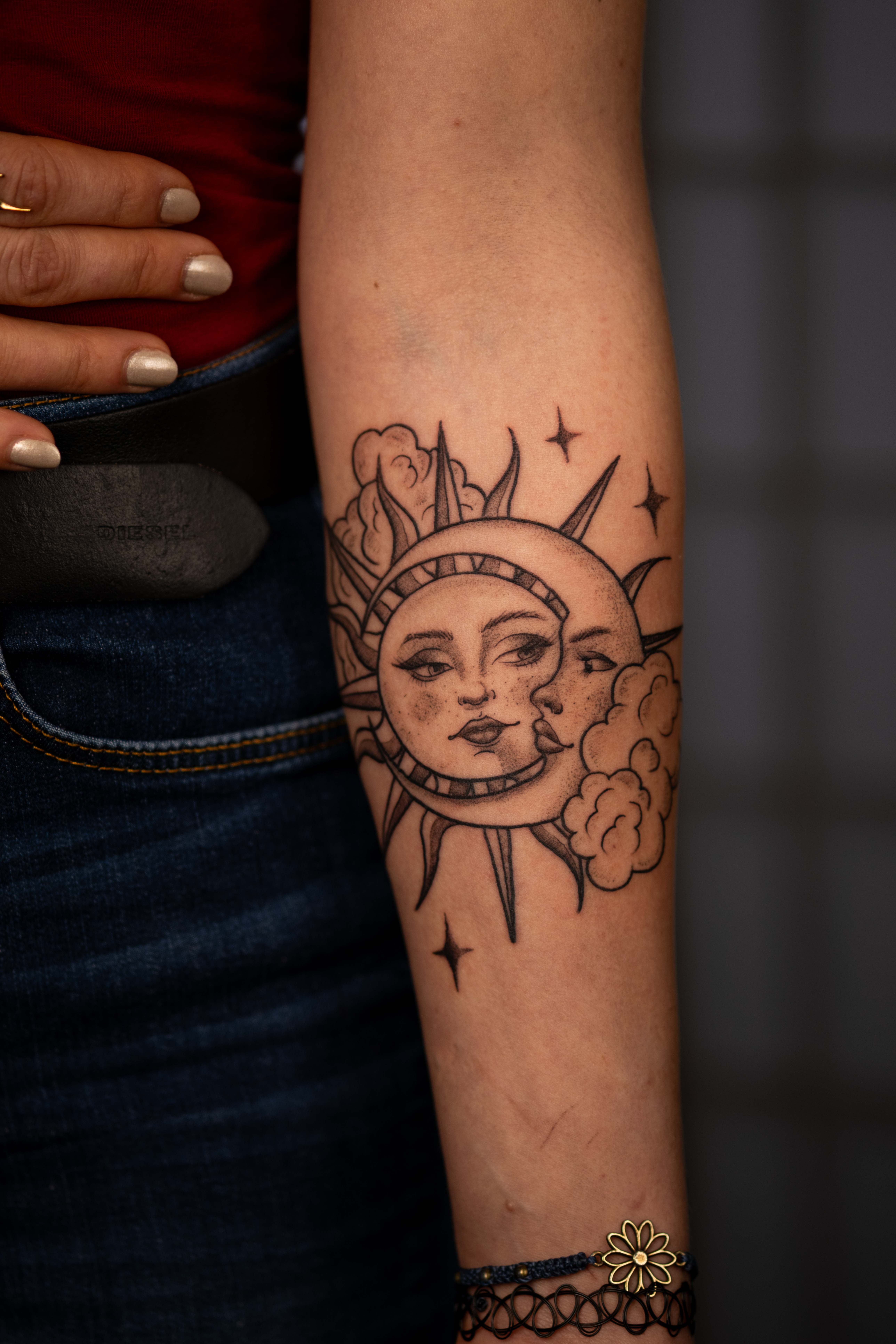Arm mit neutralem Ausdruck und schwarzem Tattoo mit Sterne und Wolken