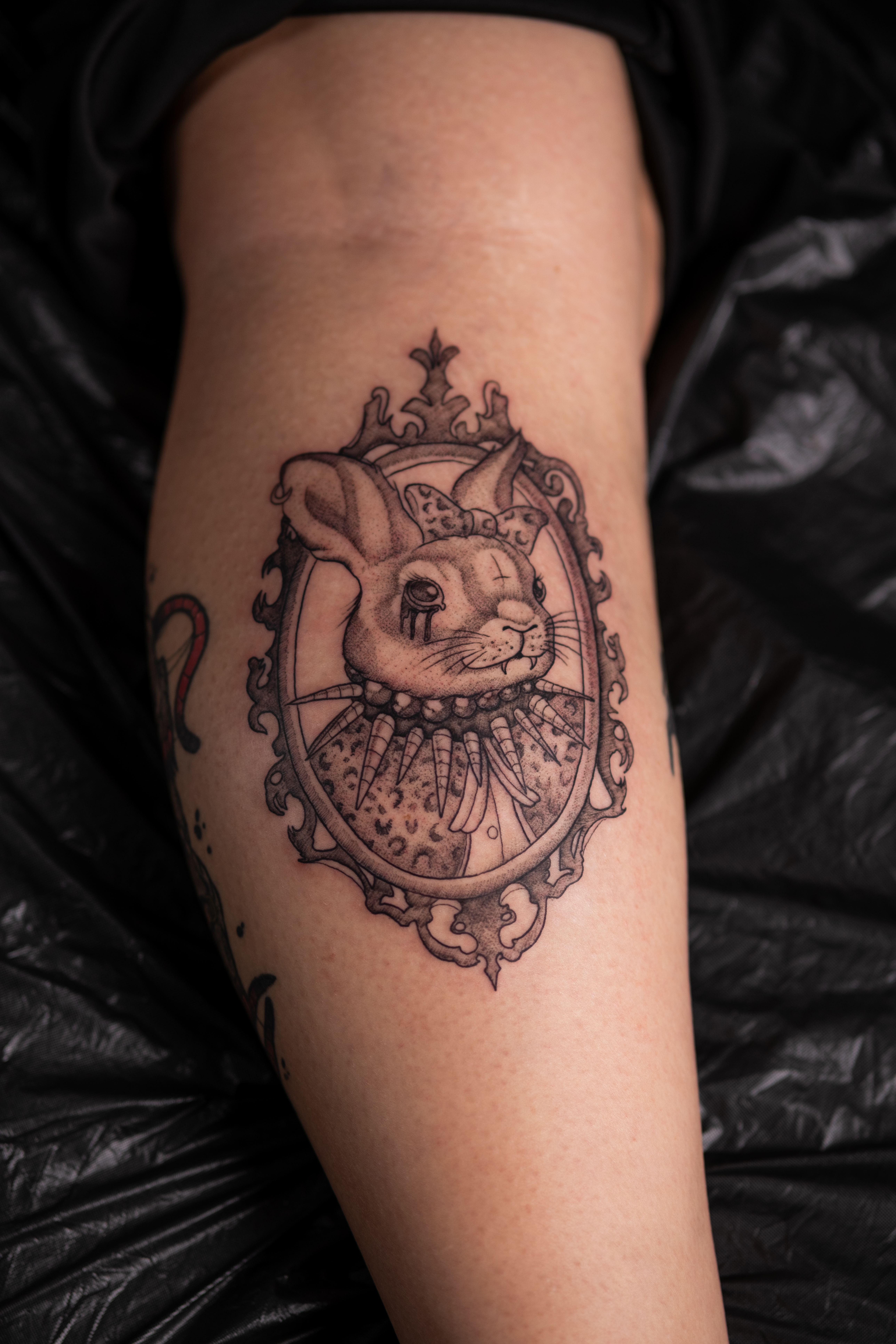 Person mit neutralem Ausdruck und schwarzgrauem Hasen Tattoo im Rahmen