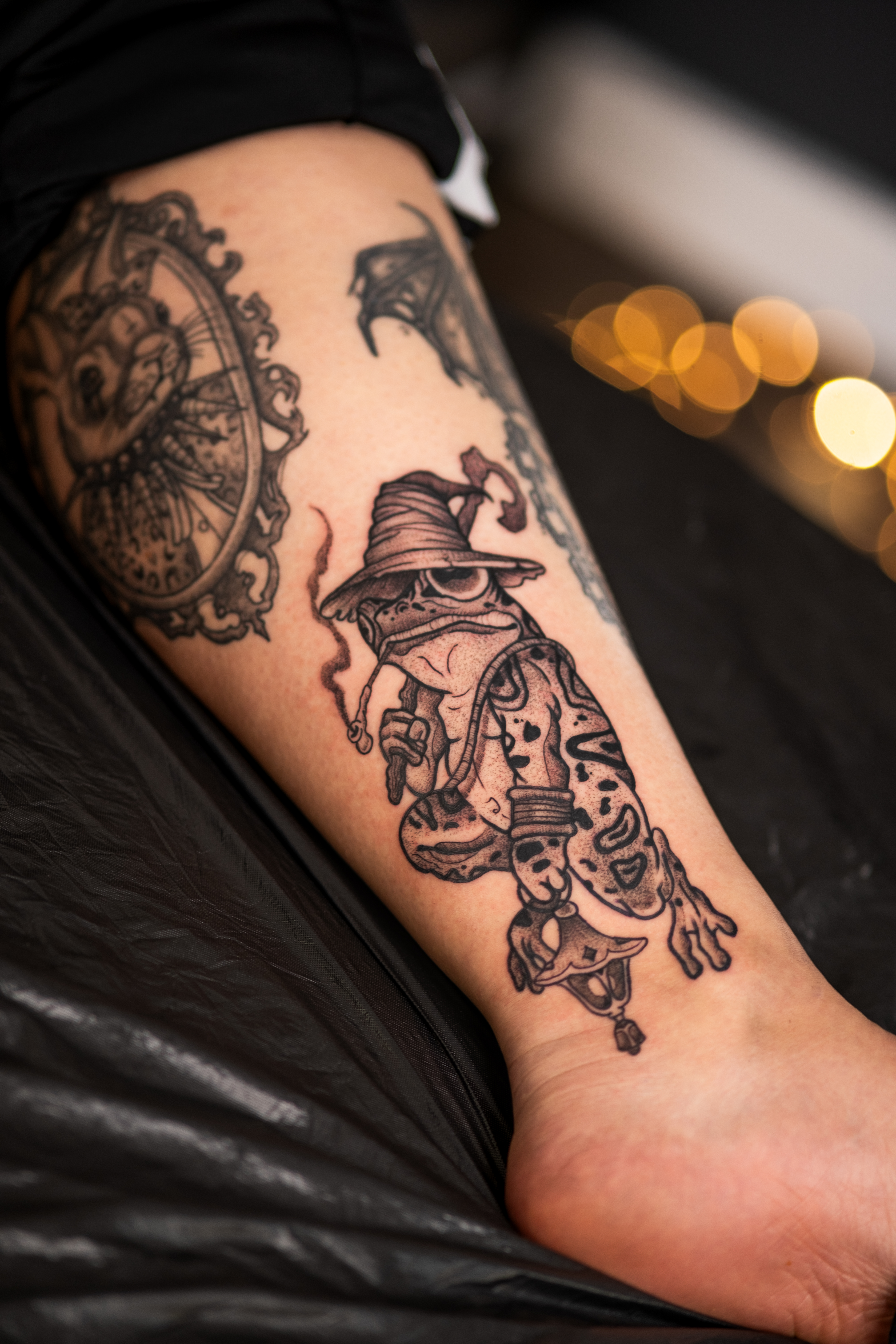 Unterarm mit neutralem Ausdruck, schwarze Tattoos von Uhr und Comicfigur